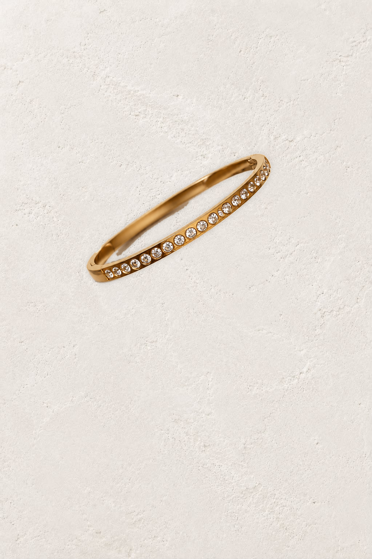 
                  
                    Amara Gold Round Crystal Bangle on the reference plaster background
                  
                