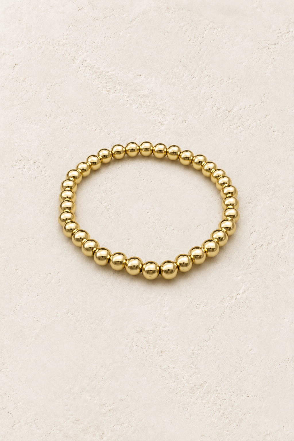 
                  
                    6mm Gold Plated Beaded Elastic Bracelet TF on Boho & Mala's cream beige textured hero background
                  
                