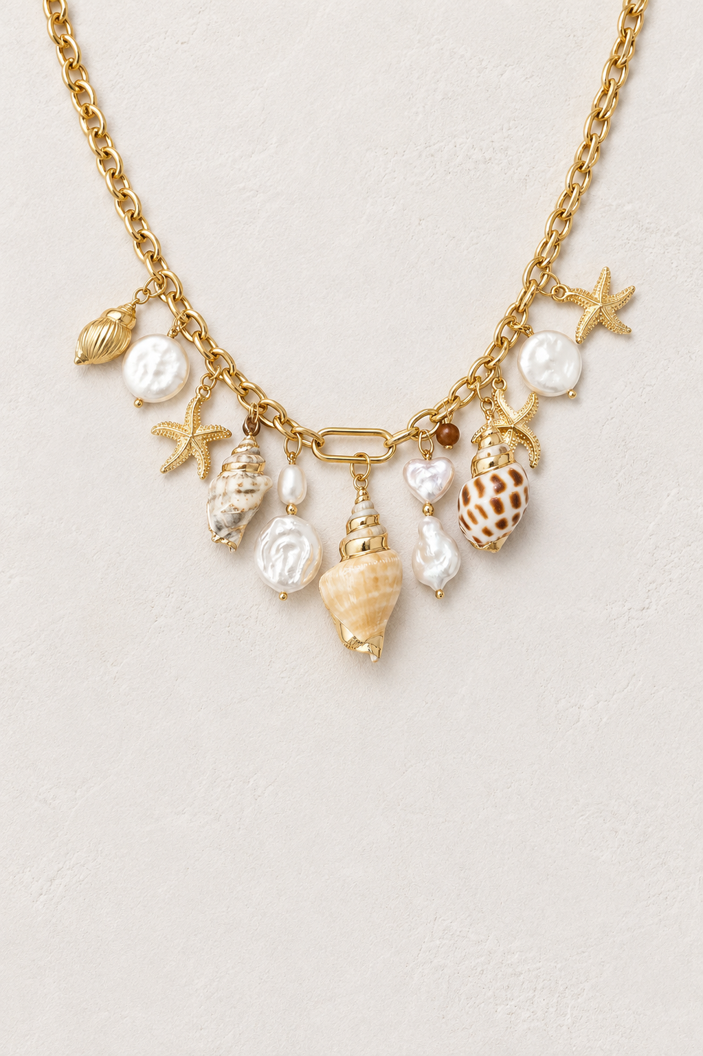 Shells & Pearls Charm Necklace in waterproof gold plated stainless steel on a warm textured background