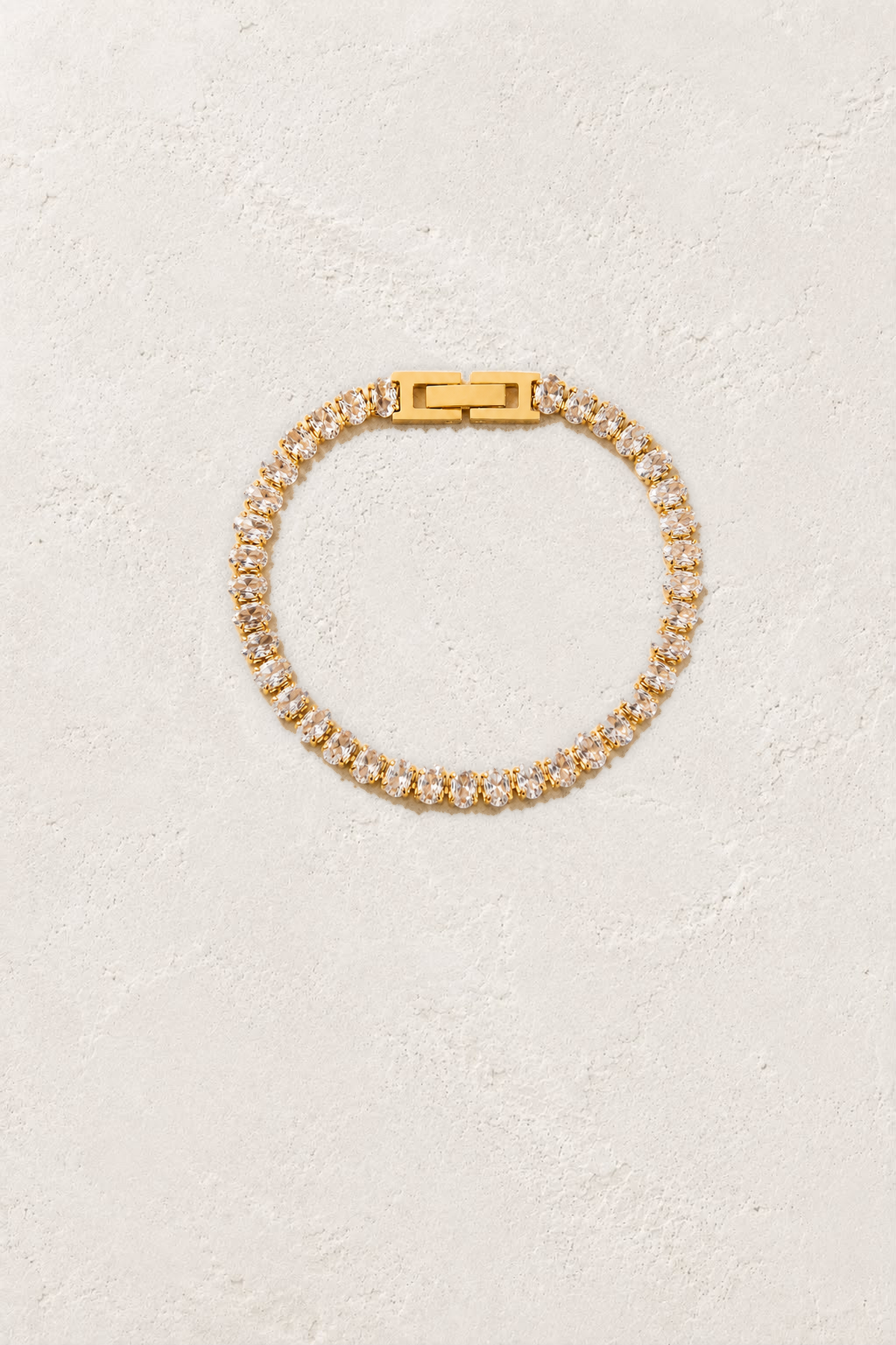 Aurora Oval Crystal Gold Tennis Bracelet on the reference plaster background