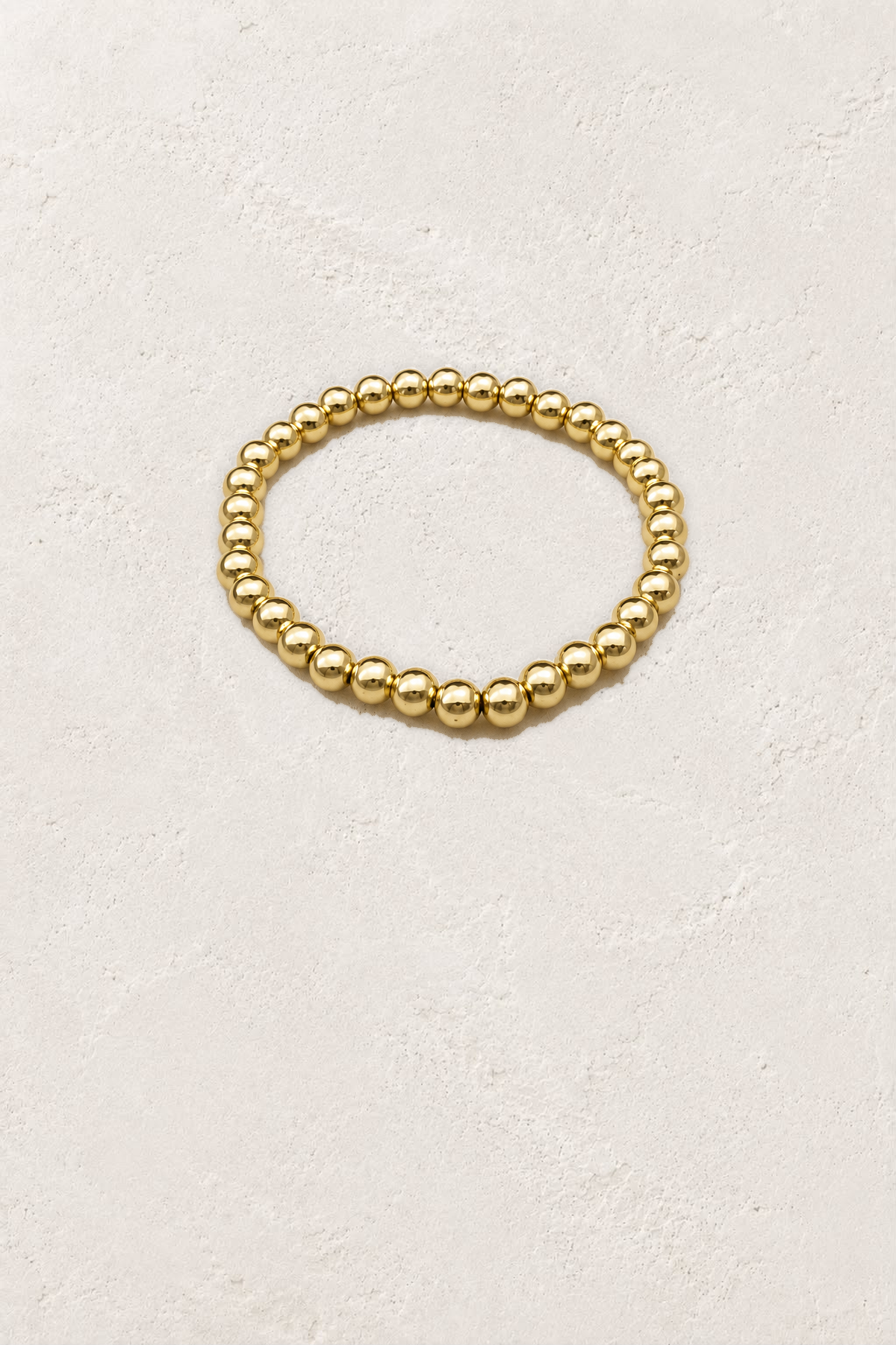 6mm Gold Plated Beaded Elastic Bracelet TF on the reference plaster background