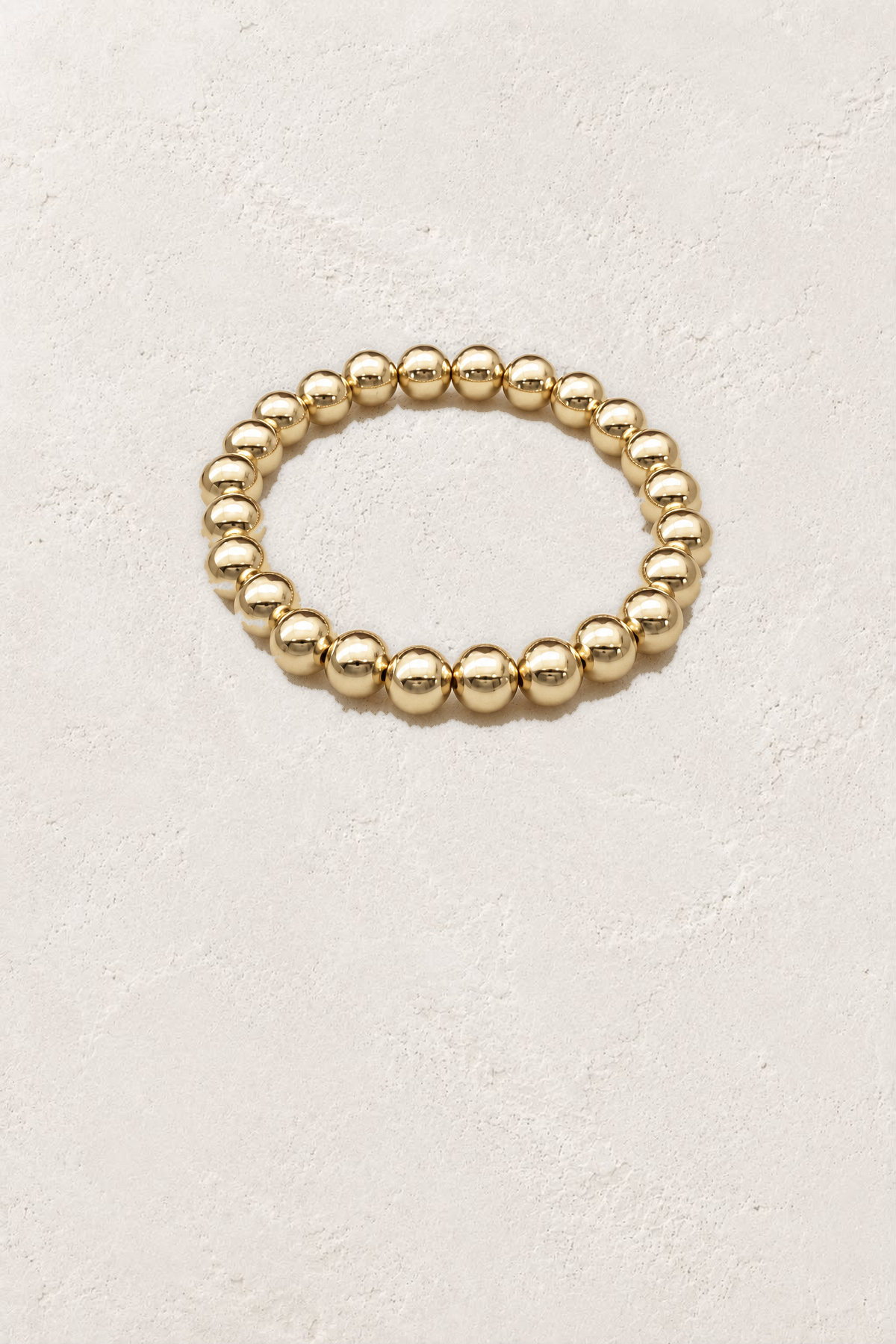 8mm Gold Plated Beaded Elastic Bracelet TF on the reference plaster background