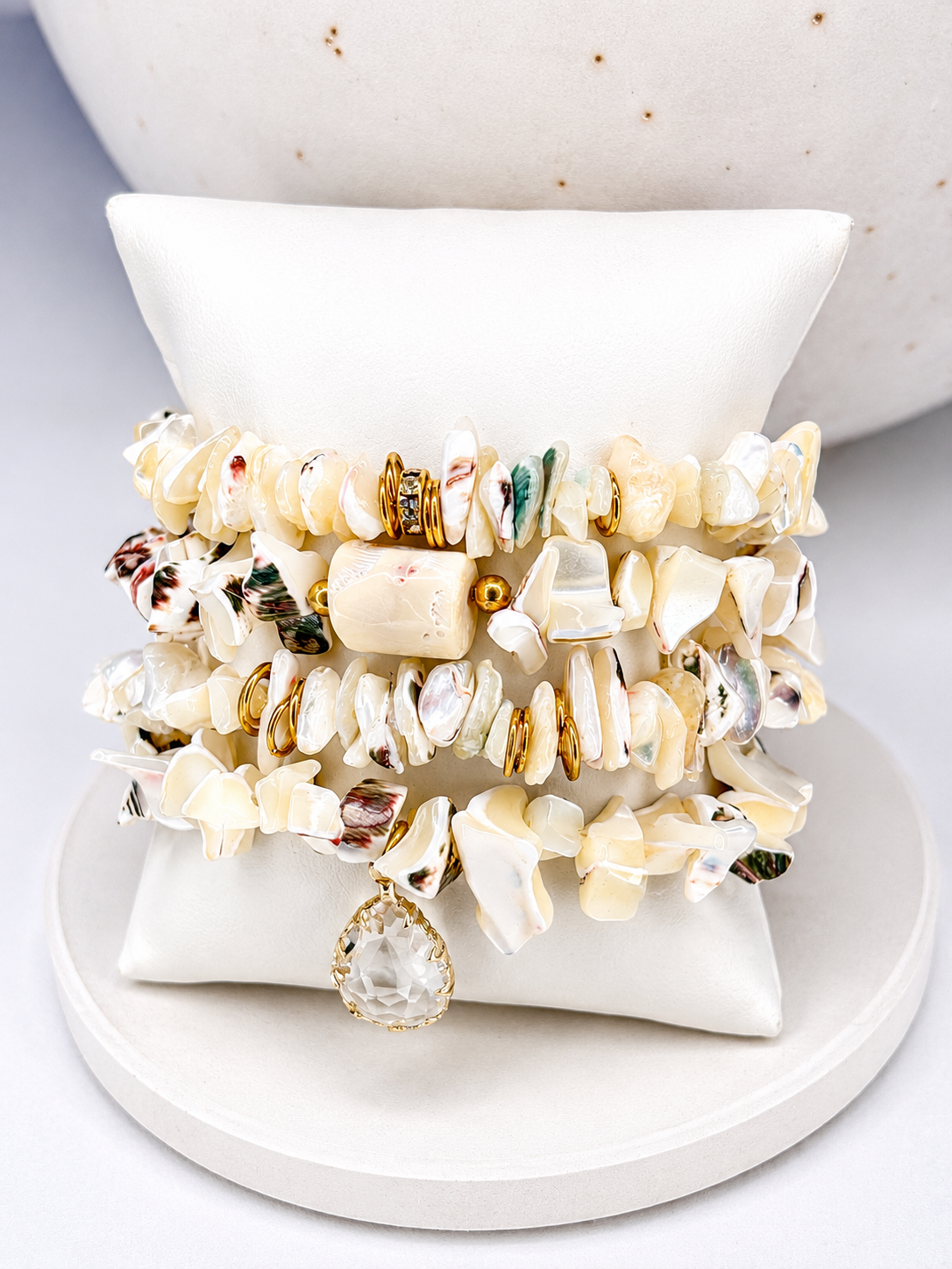Stack of shell bracelets on a white dish with a neutral background