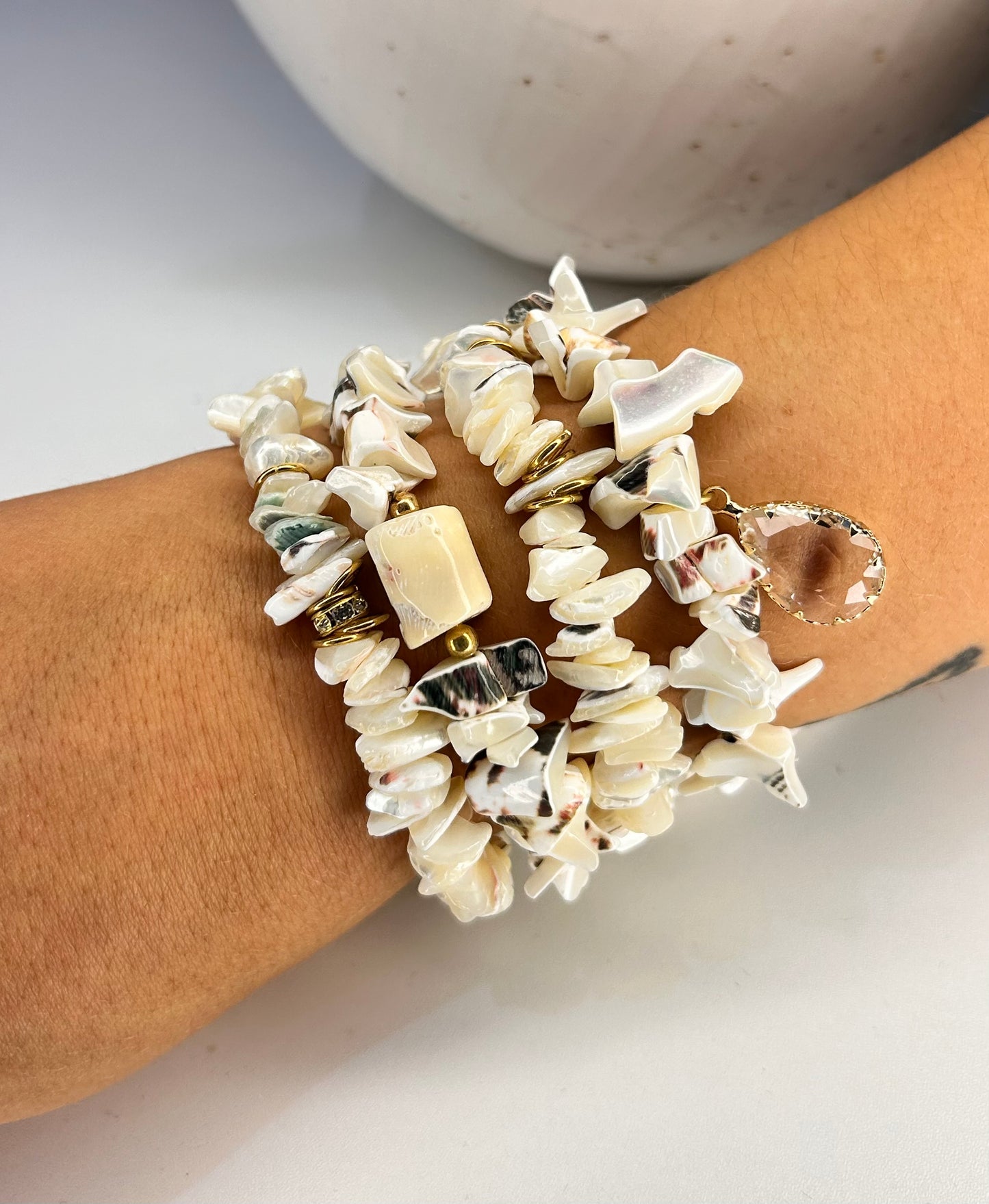 Shell bracelet on a wrist with a neutral background