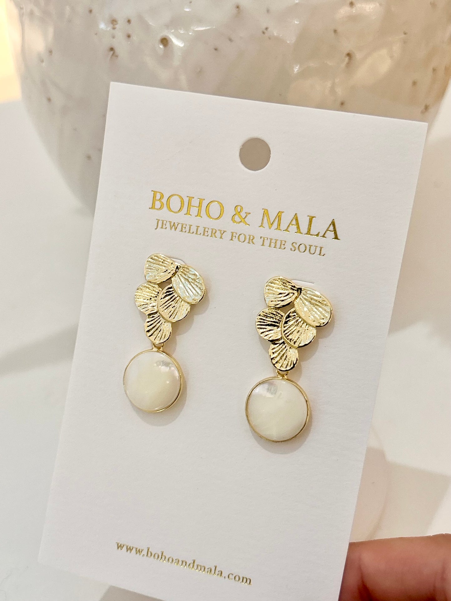 
                  
                    Gold and white earrings on a BOHO & MALA branded card.
                  
                
