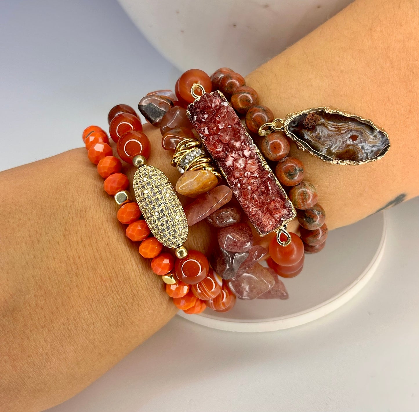 Stack of colorful natural beaded bracelets on a wrist with a neutral background