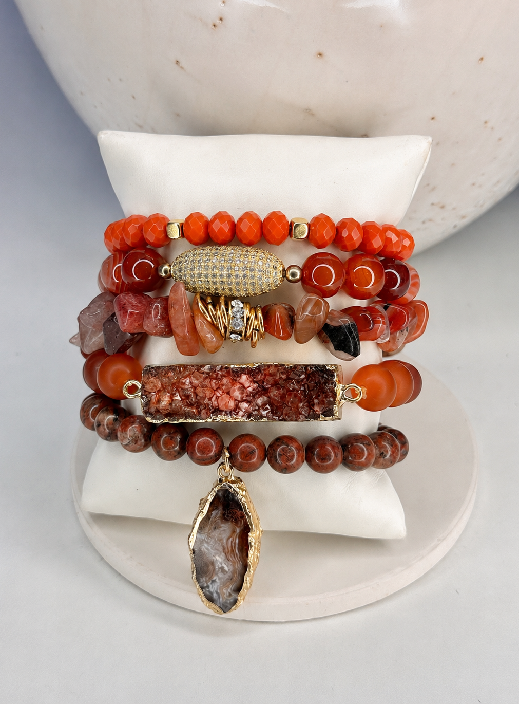 Stack of beaded bracelets with natural stone and gold accents on a white surface.