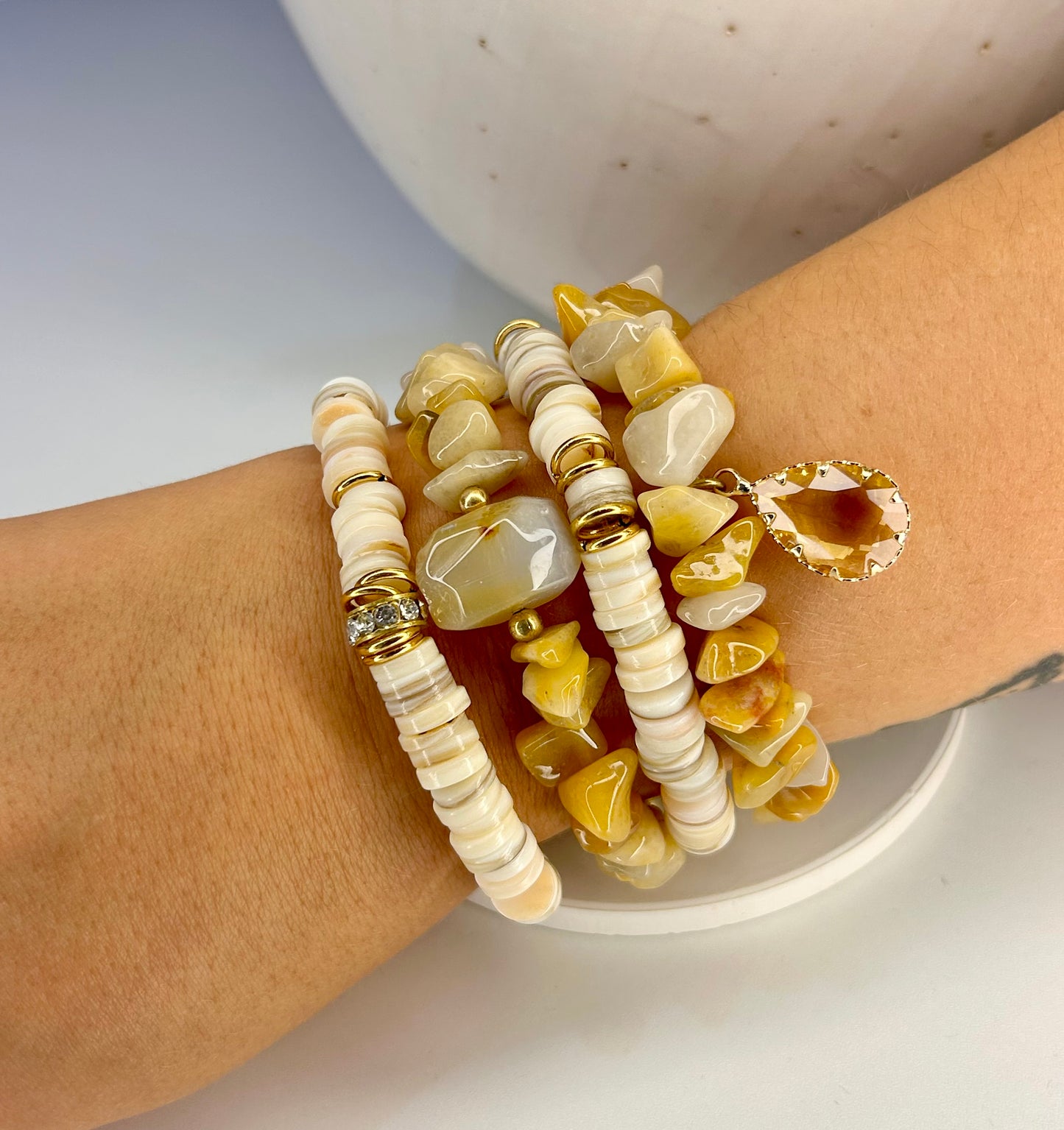 Stack of beaded natural stone bracelets on a wrist with a neutral background
