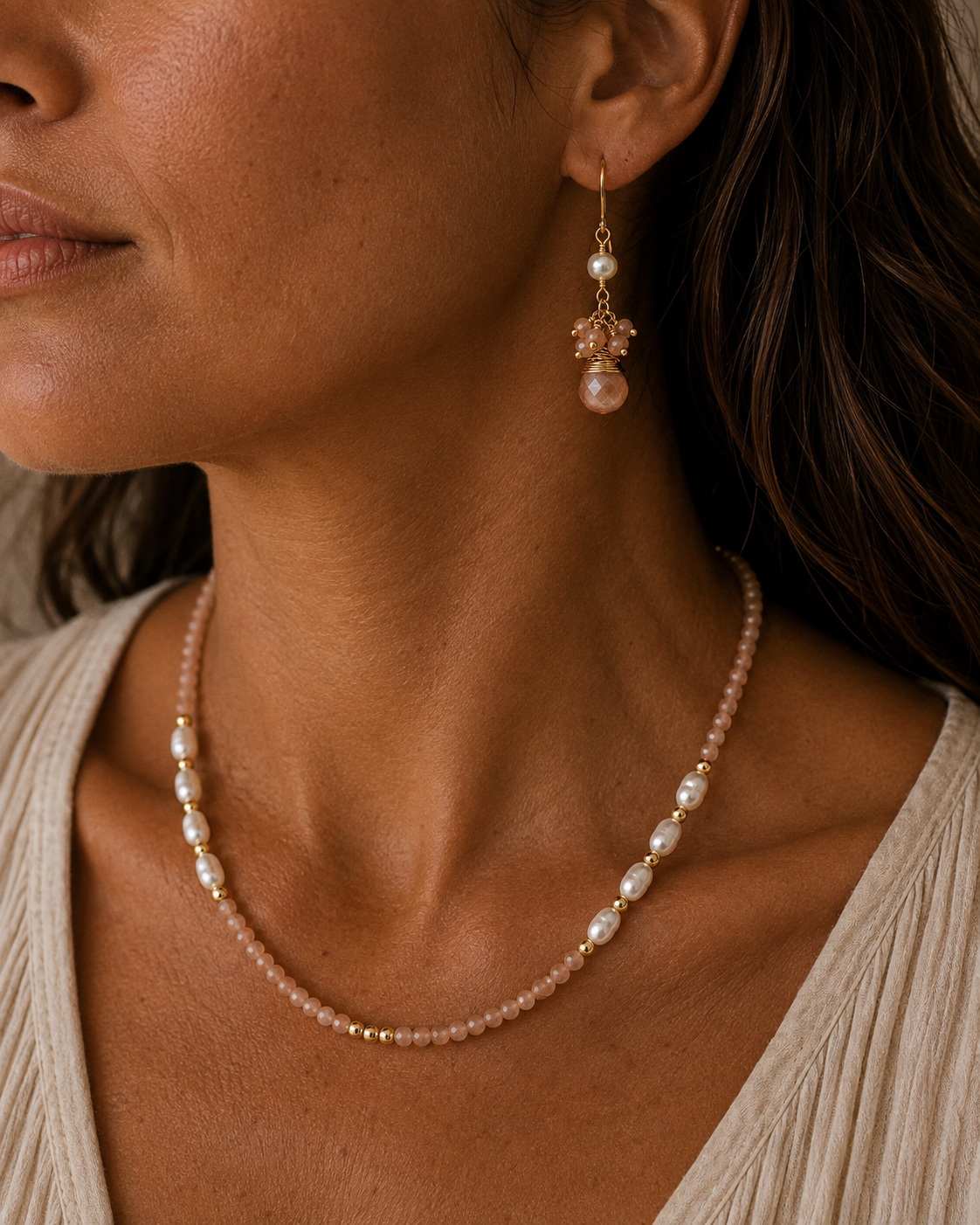 
                  
                    A close-up of a woman wearing a delicate gold and pearl necklace with a matching drop earring, showing the jewelry on her neck and ear.
                  
                