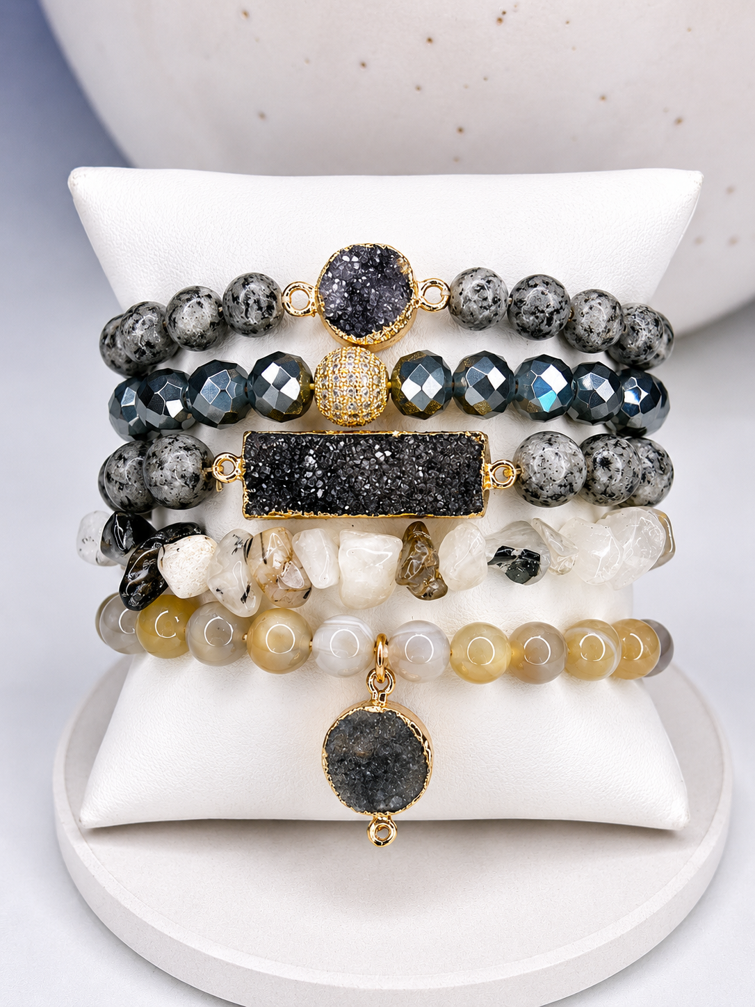 Stack of beaded bracelets with gold accents on a white surface with real natural gemstones 