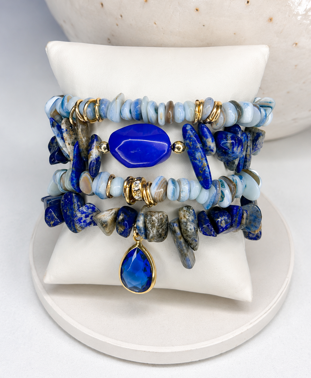 Set of blue and gold beaded bracelets on a white surface with a mix of lapis lazuli stones 