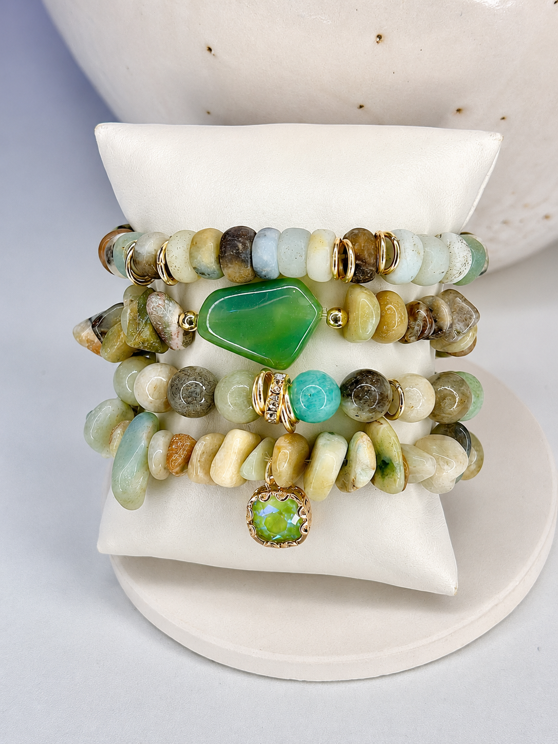 Set of beaded mixed green stone bracelets with green and gold stones on a white surface