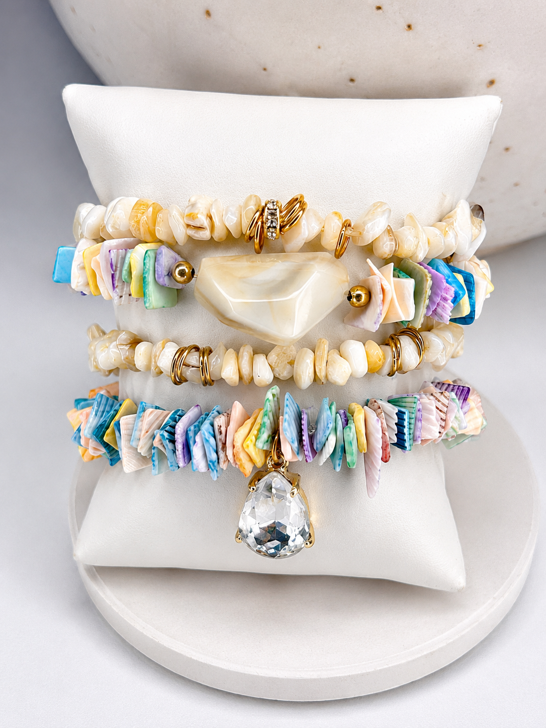 
                  
                    Set of colourful shell beaded bracelets on a white surface
                  
                