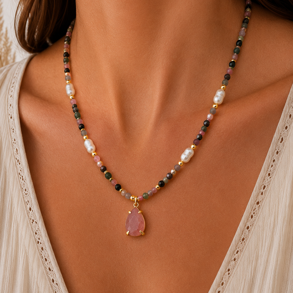 A close-up of a woman wearing a delicate beaded necklace with a sunstone teardrop pendant. The necklace features small  mixed sunstone beads, white freshwater pearl beads, and gold-toned metal accents.