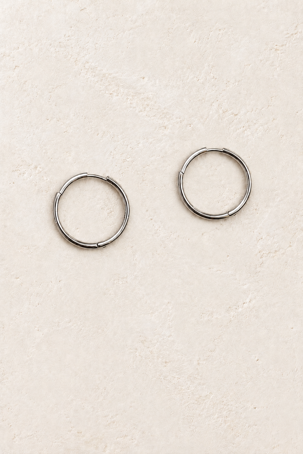 
                  
                    Arlette Silver Slim Hoop Earrings on warm ivory plaster
                  
                