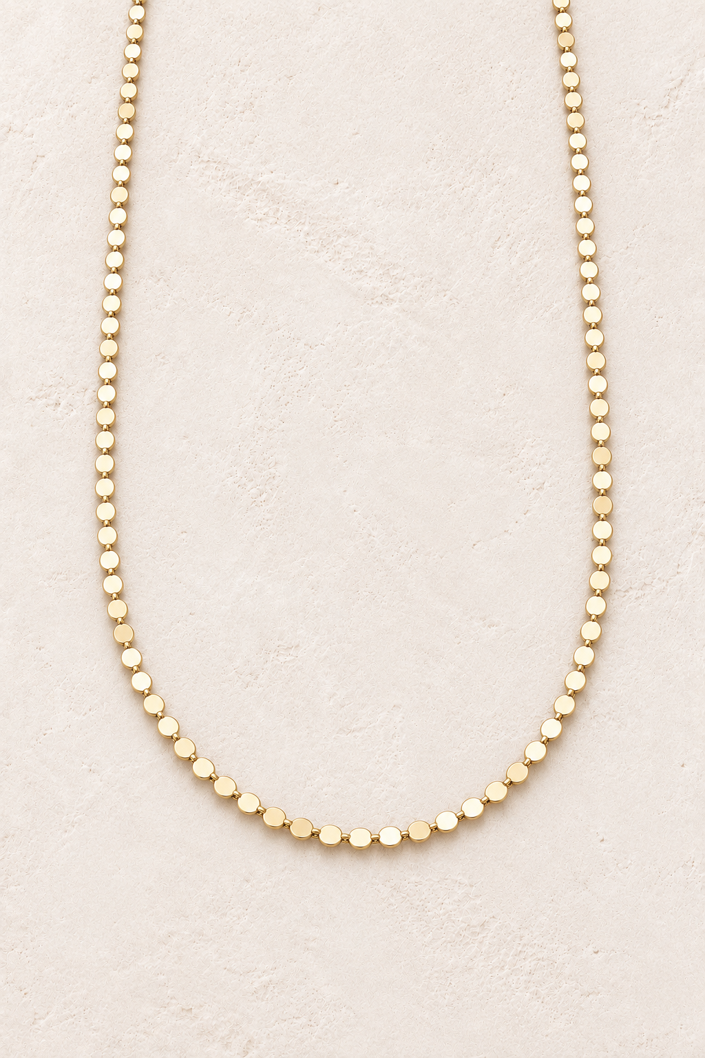 Aurelia Gold Disc Chain Necklace on warm ivory textured background