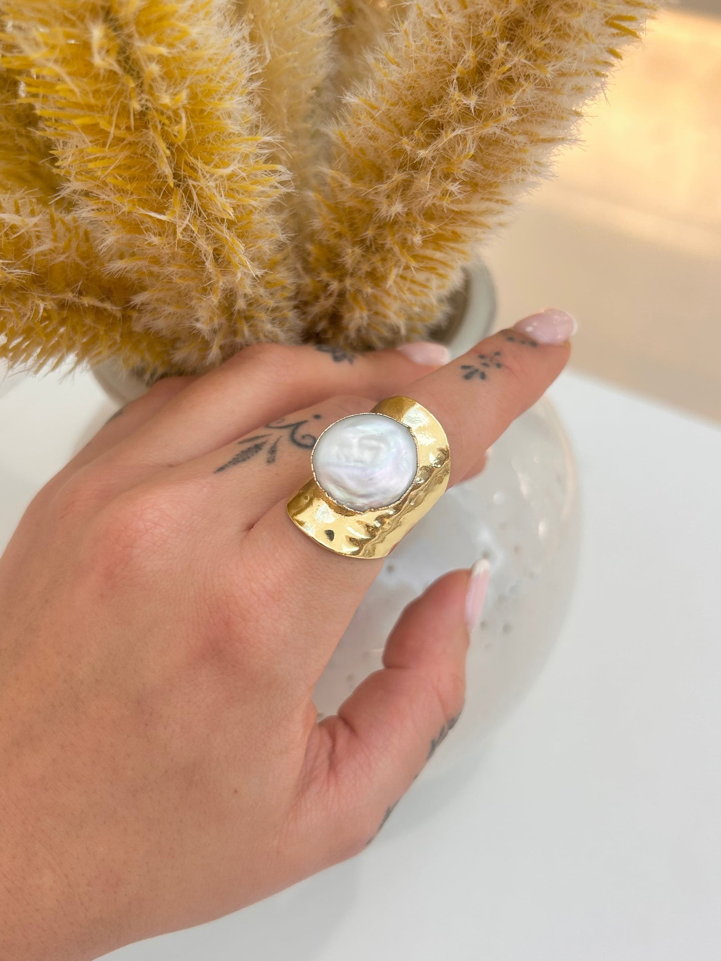 Hand wearing the Aureline Freshwater Pearl Statement Ring featuring a luminous natural pearl and sculptural hammered gold-plated band.