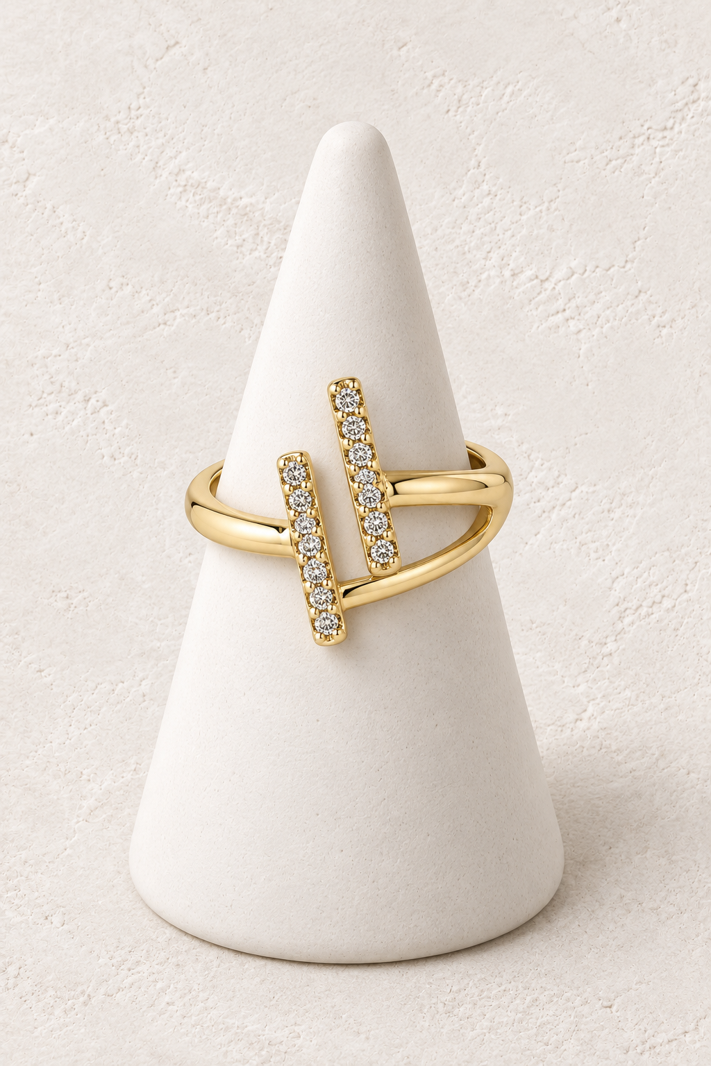 Aurelle Double Bar Ring on a white display cone against a warm textured background