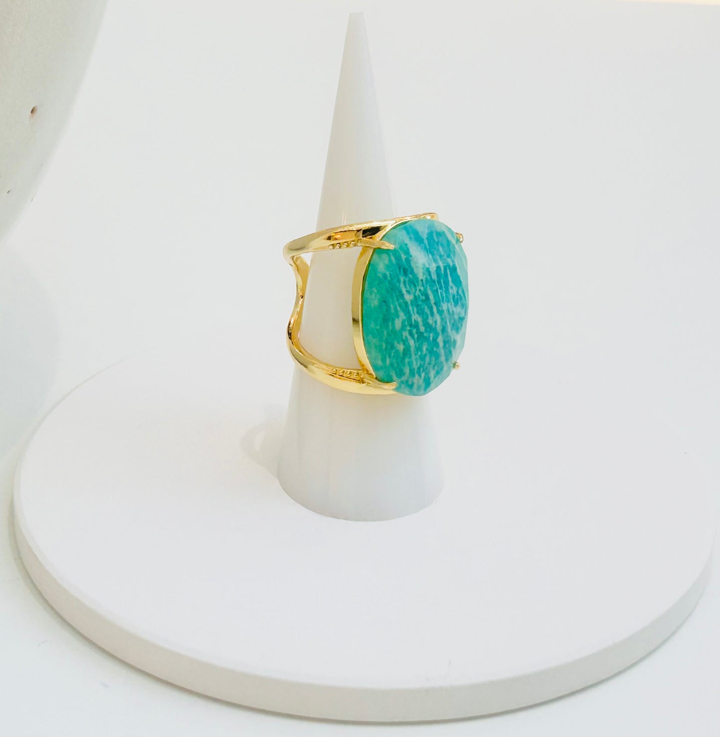 
                  
                    A gold ring with a large oval amazonite stone, displayed on a white cone stand against a white background.
                  
                