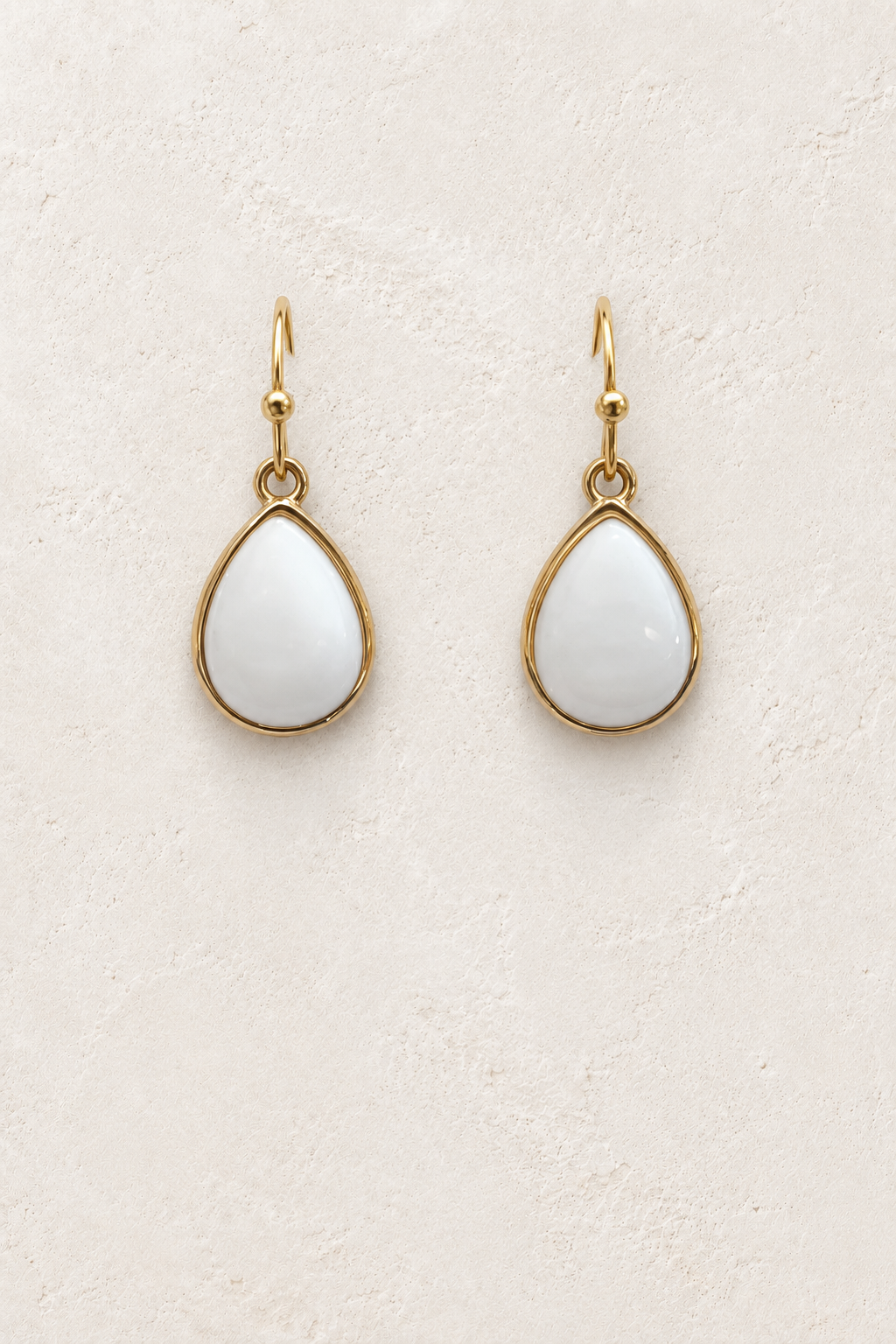Aviana Milky Quartz Teardrop Earrings on cream plaster background