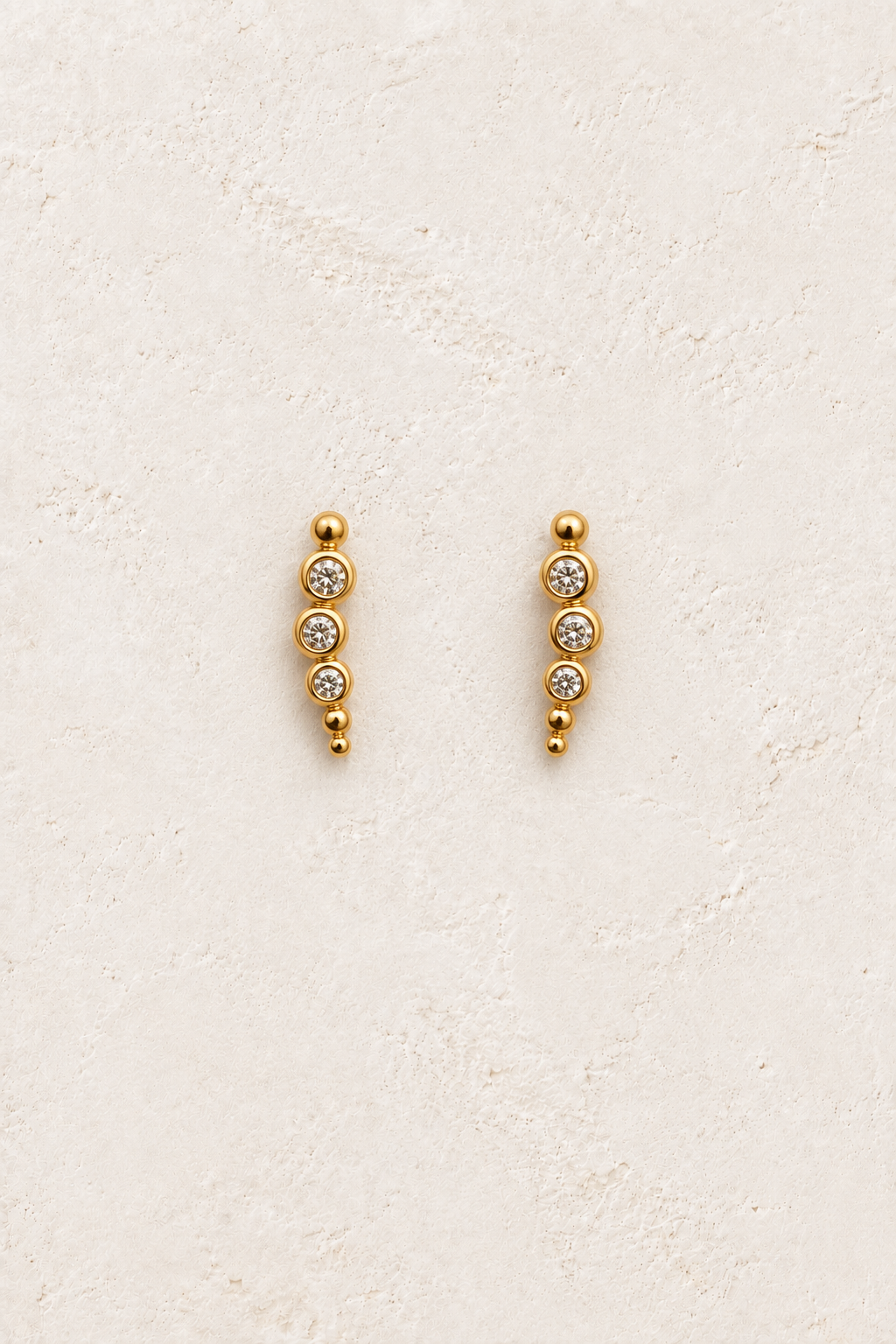 Ayla Triple Spark Studs on warm ivory textured background
