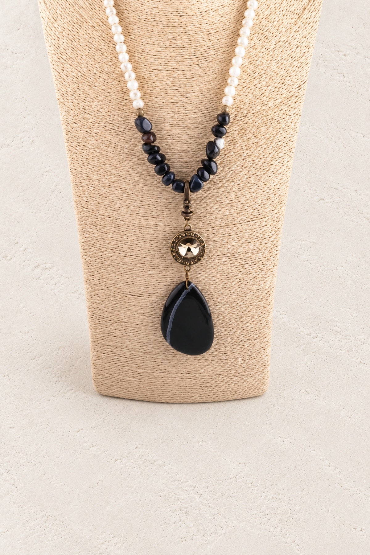 Black Stone Tribal Teardrop Necklace on warm cream plaster background