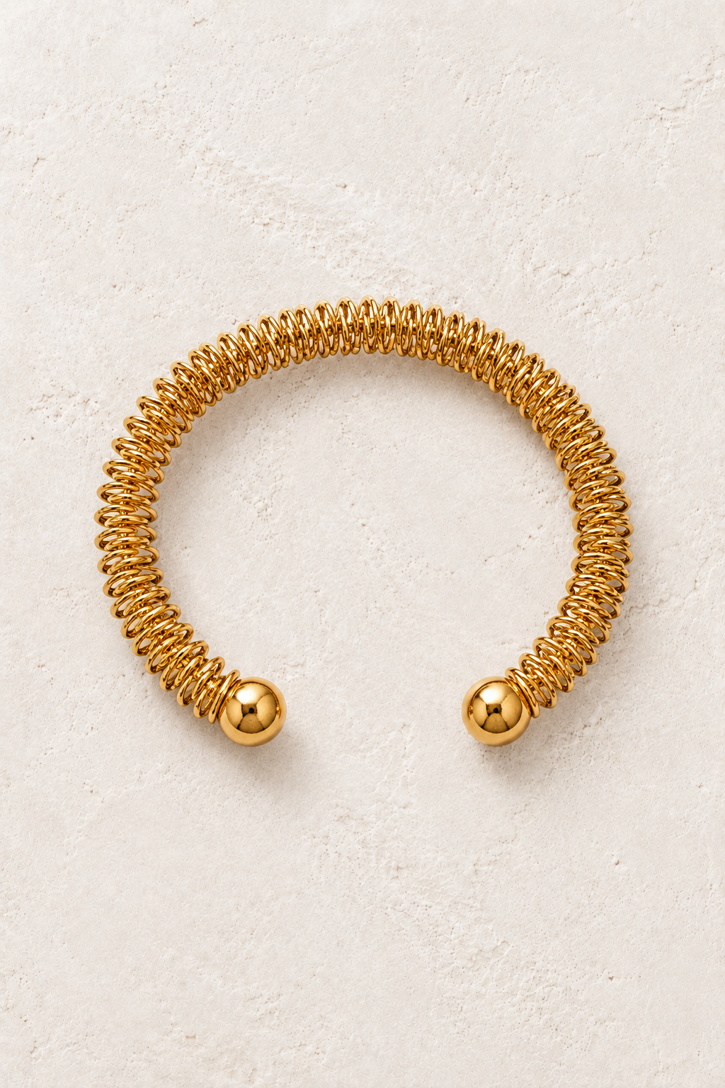
                  
                    Gold Coil Open Cuff Bracelet | Waterproof on ivory textured background
                  
                