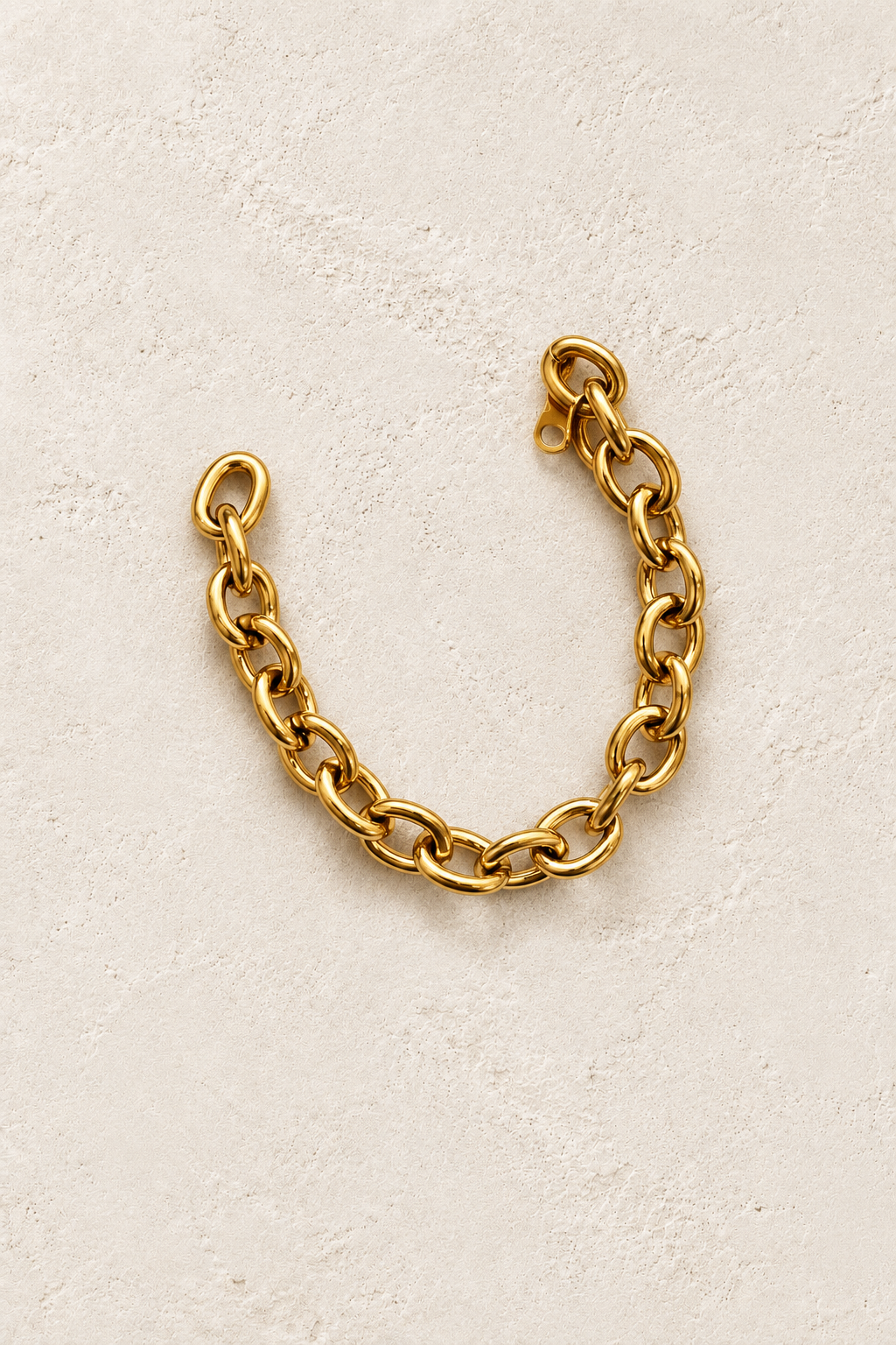 
                  
                    Brielle Gold Classic Oval Link Bracelet on cream beige textured background
                  
                