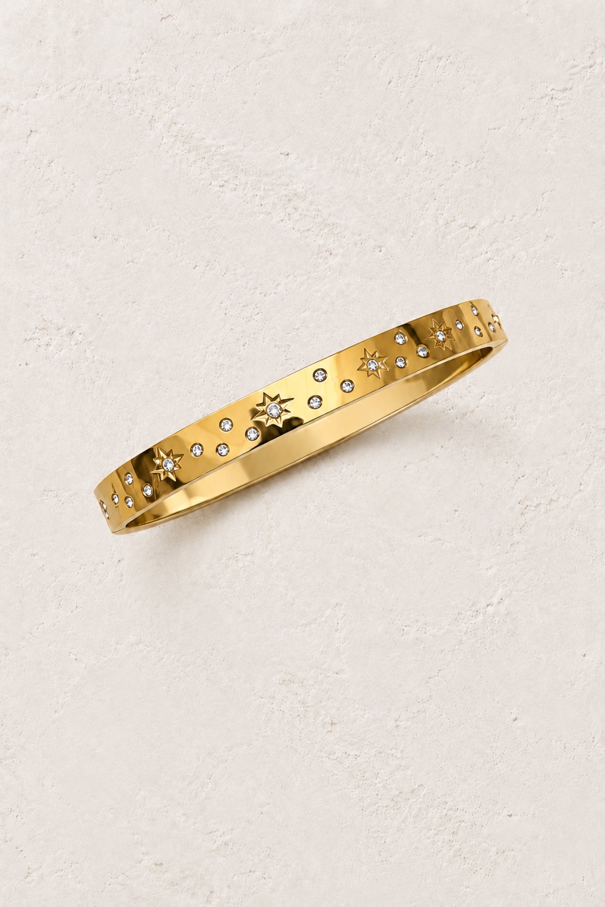 
                  
                    Celestra Gold Starburst Bangle on Boho & Mala's ivory plaster background
                  
                