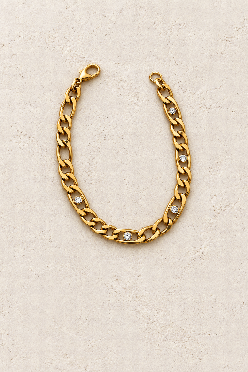 
                  
                    Clarisse Gold Crystal Figaro Bracelet on cream beige textured background
                  
                