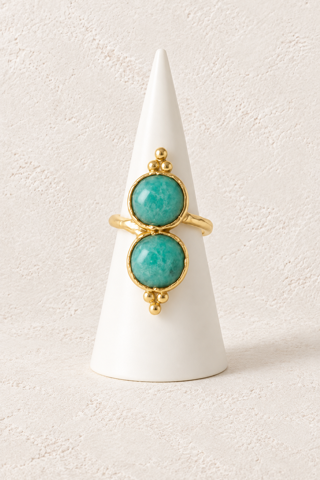 Elaria Double Amazonite Ring on a white display cone against a warm textured background
