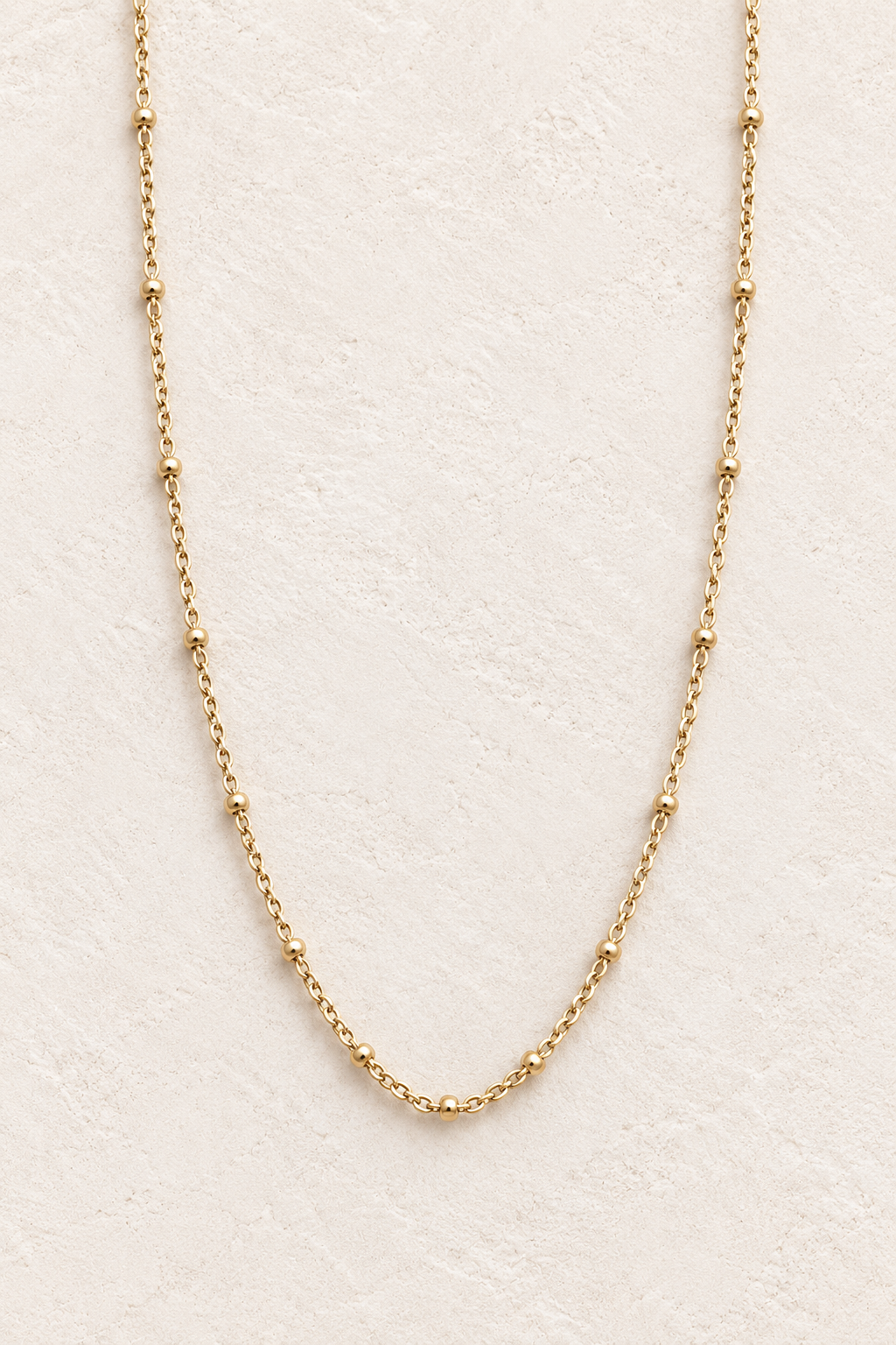 Elaria Gold Chain Necklace on warm ivory textured background