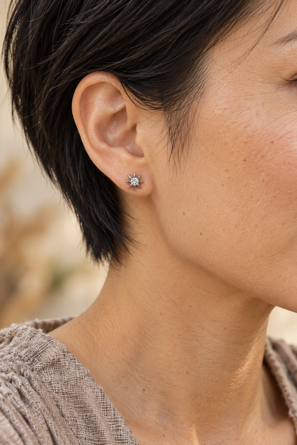 
                  
                    Close-up of Estelle Silver Starburst Stud Earrings worn on a boho chic model
                  
                