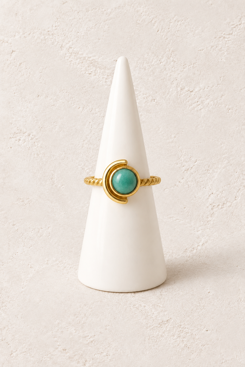 Evadne Amazonite Orbit Ring on a white display cone against a warm textured background