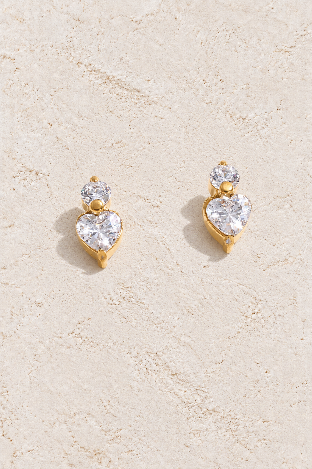 gold cubic zirconia heart stud earrings on cream plaster