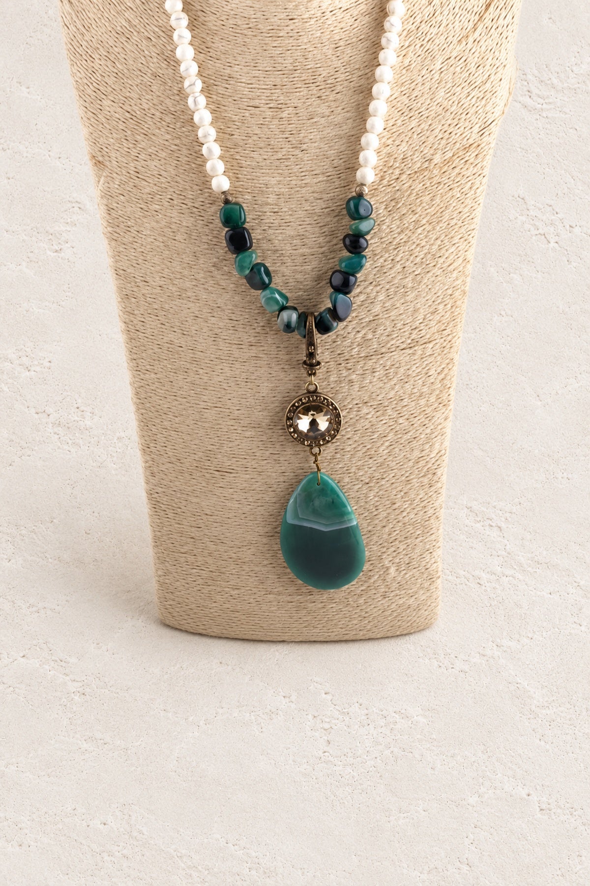 
                  
                    Green Stone Tribal Teardrop Necklace on warm cream plaster background
                  
                
