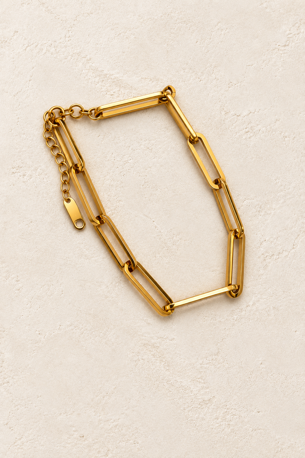 
                  
                    Greta Gold Long Paperclip Bracelet on cream beige textured background
                  
                