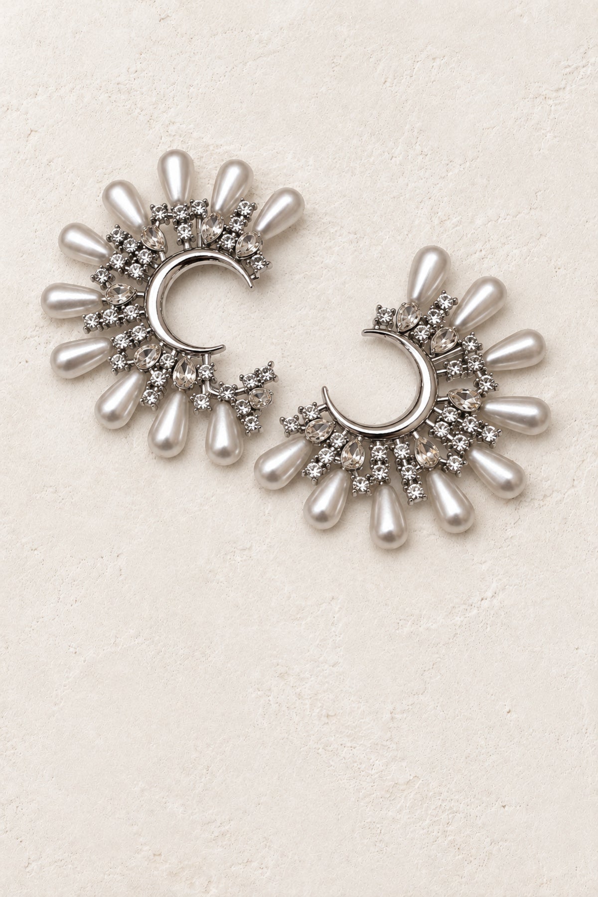 Isadora Silver Pearl & Crystal Crescent Earrings on warm ivory plaster