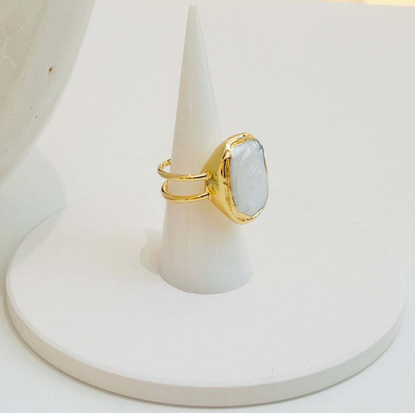 
                  
                    Avenelle Freshwater Pearl Statement Ring displayed on a white jewellery stand, featuring a natural oval pearl in a textured gold-plated setting.
                  
                
