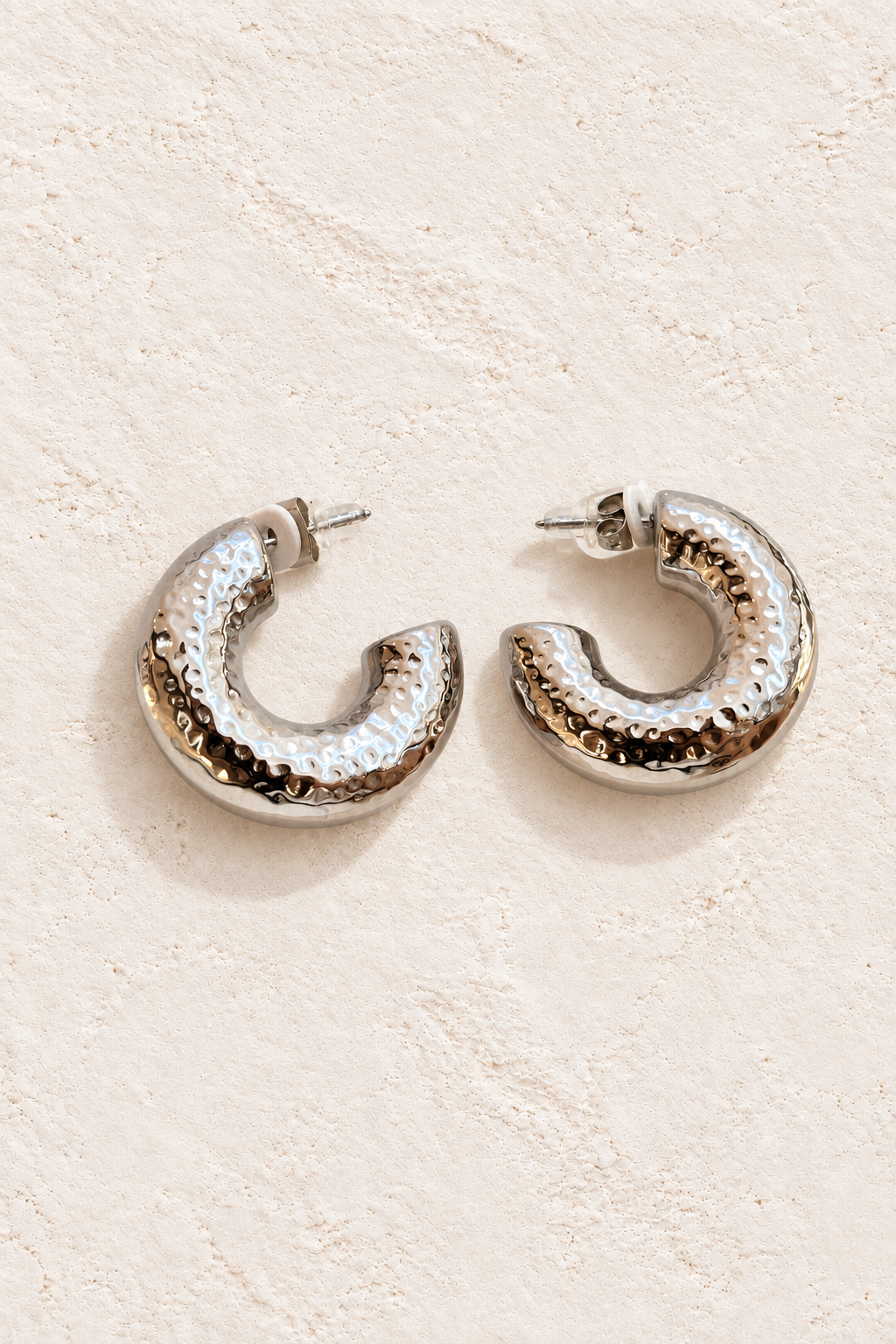Kaia Hammered Silver Hoops on warm ivory textured background