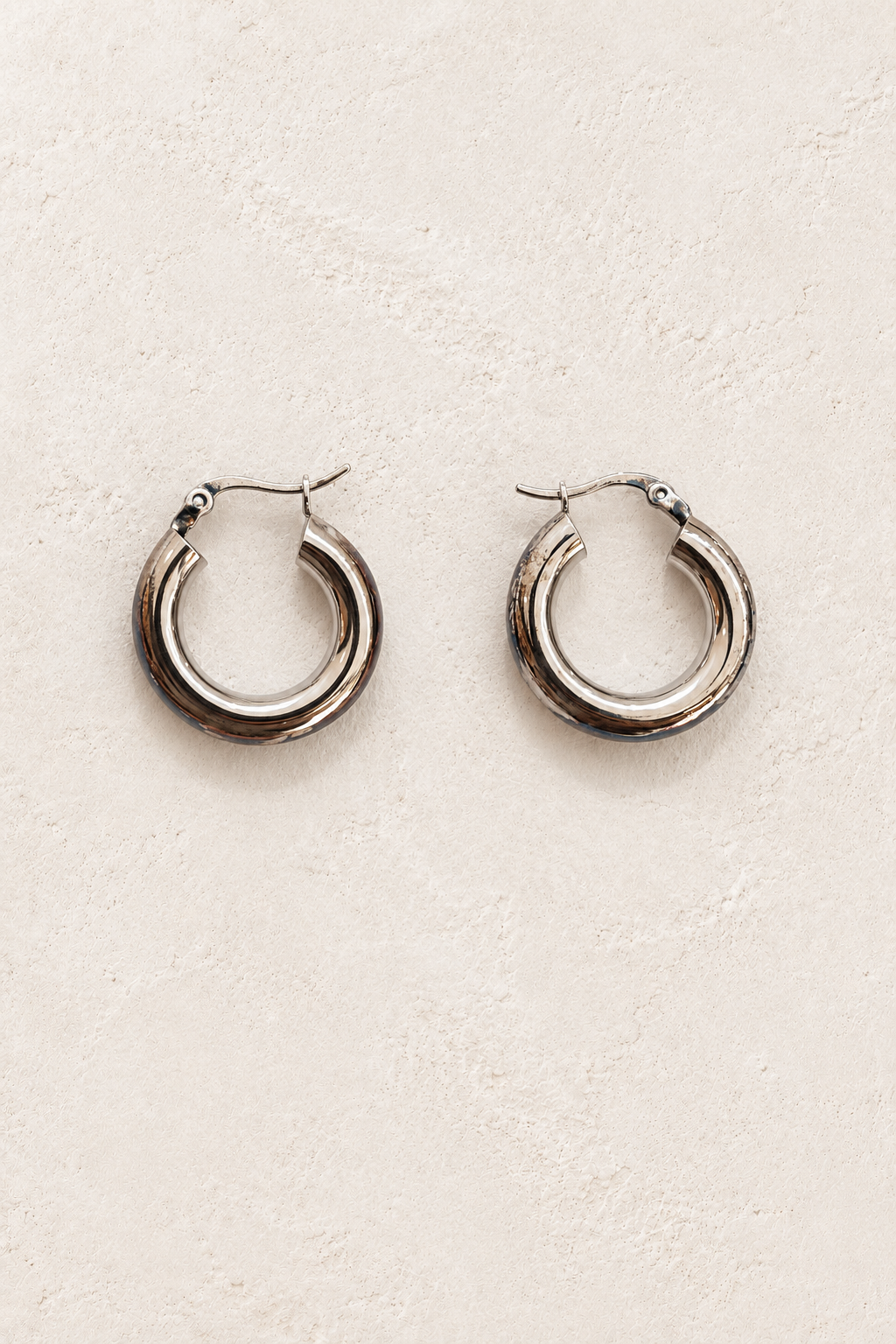 Leonora Silver Rounded Hoop Earrings on warm ivory plaster