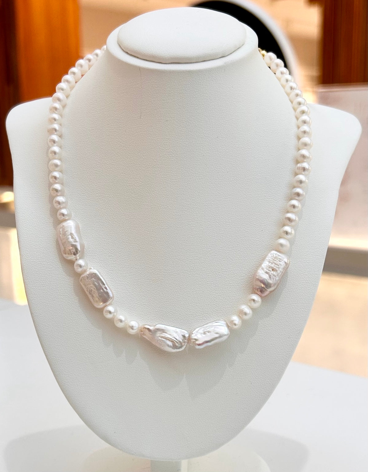 
                  
                    Lucienne mixed-shape freshwater pearl necklace displayed on a jewellery bust
                  
                