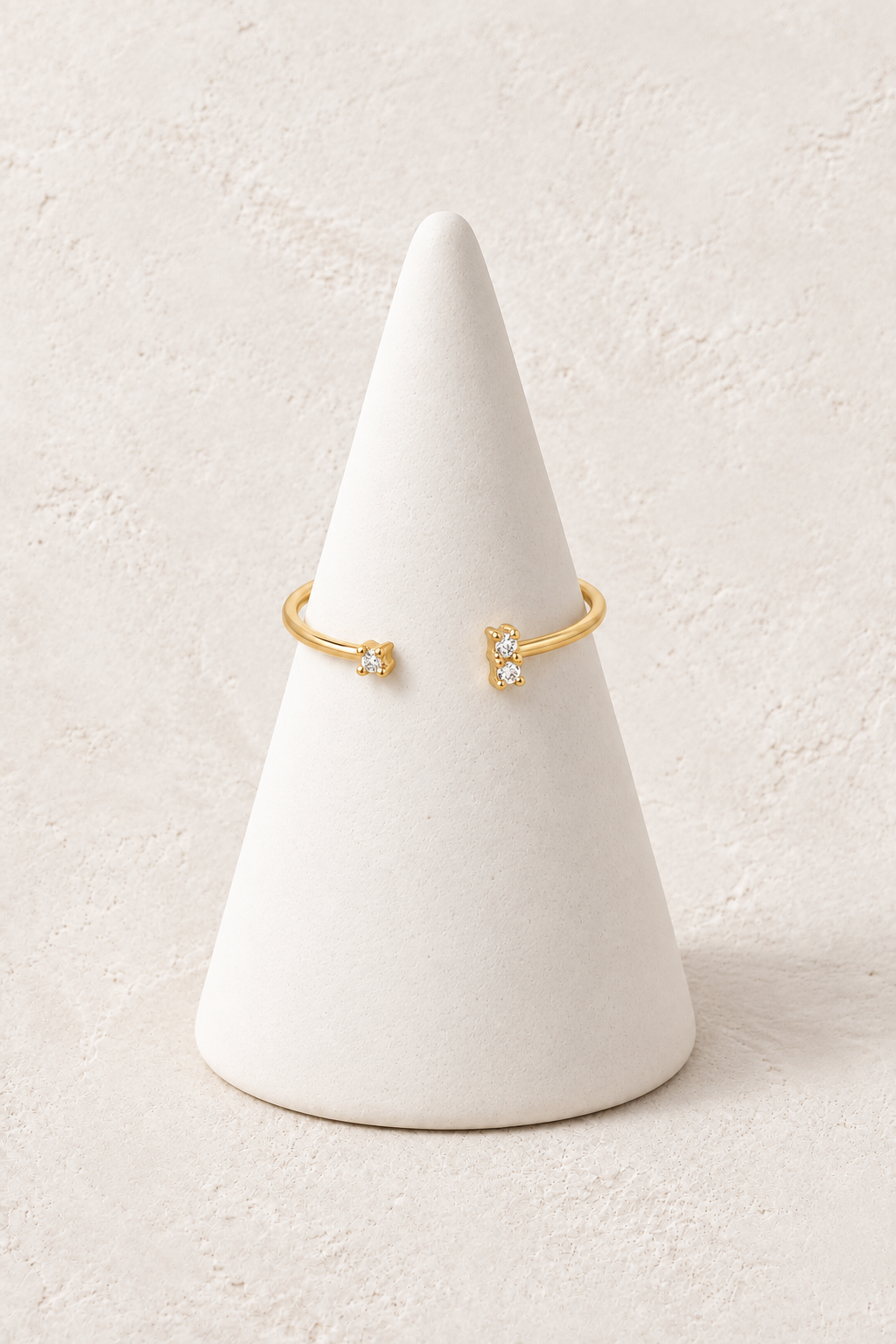 Lyra Celestial Dainty Ring on a white display cone against a warm textured background