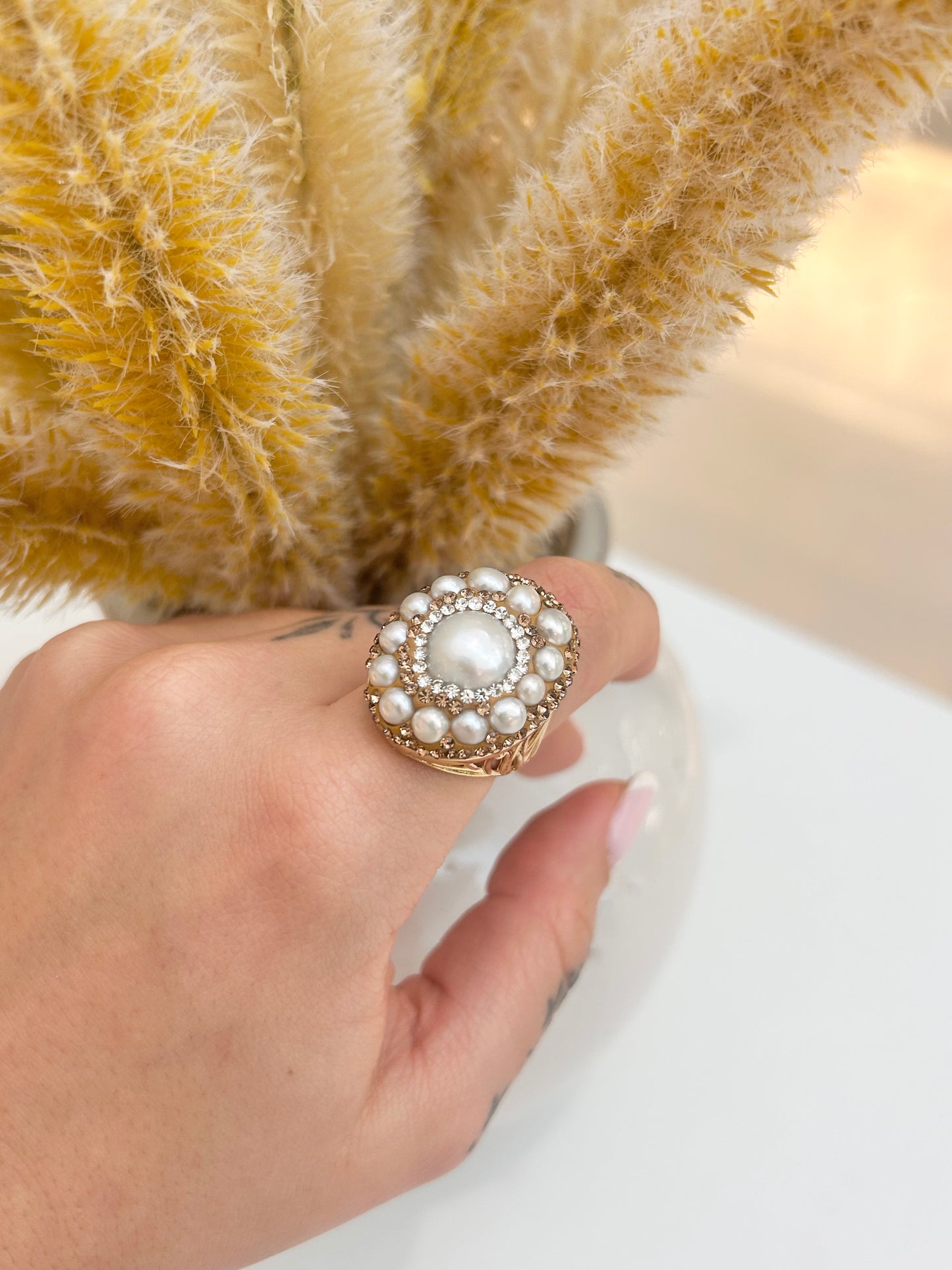 Hand wearing the Maravelle Freshwater Pearl Statement Ring featuring genuine pearls and crystal accents in an ornate gold-plated design.