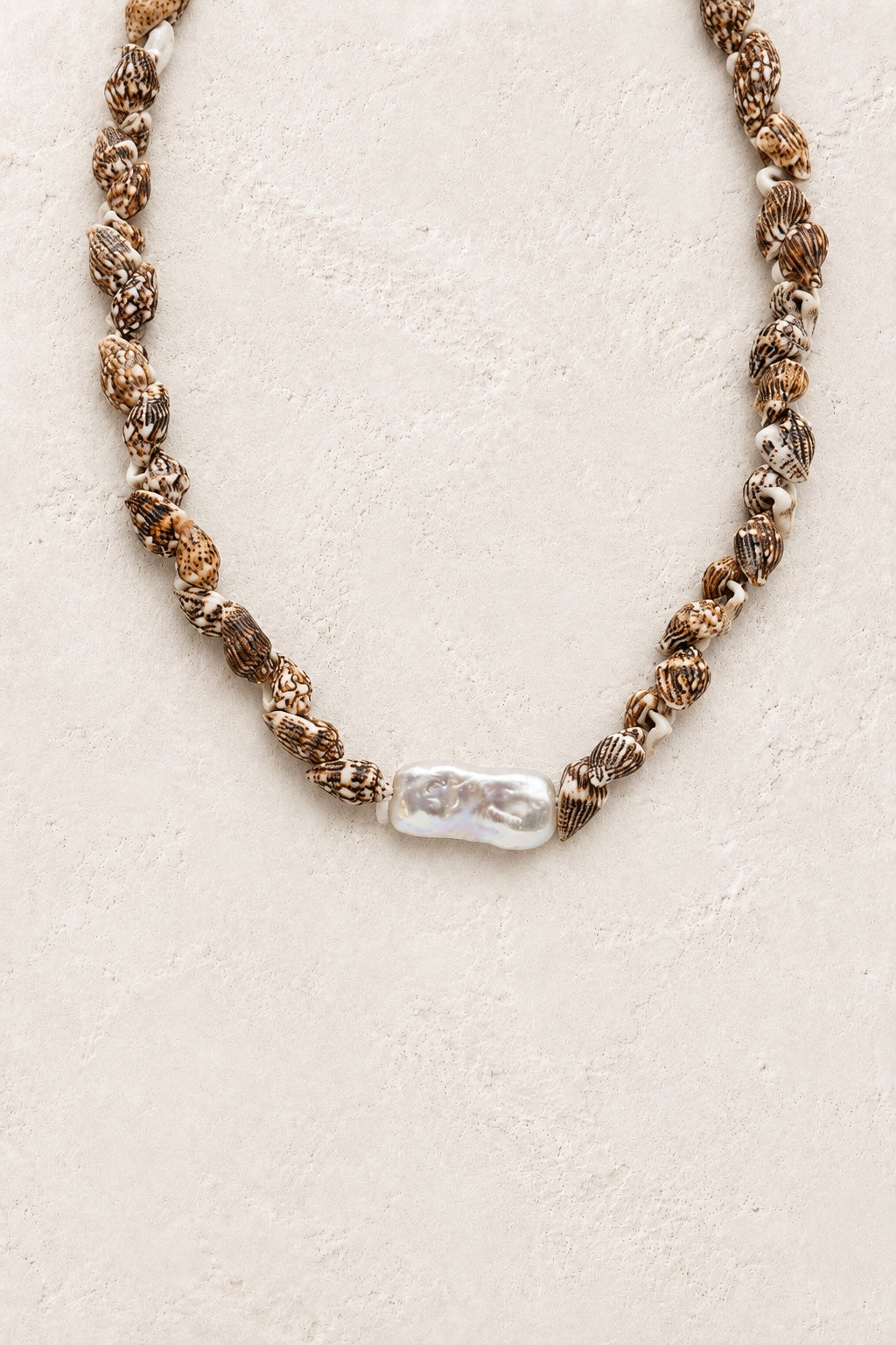Marisol patterned shell necklace with statement freshwater pearl on a neutral background