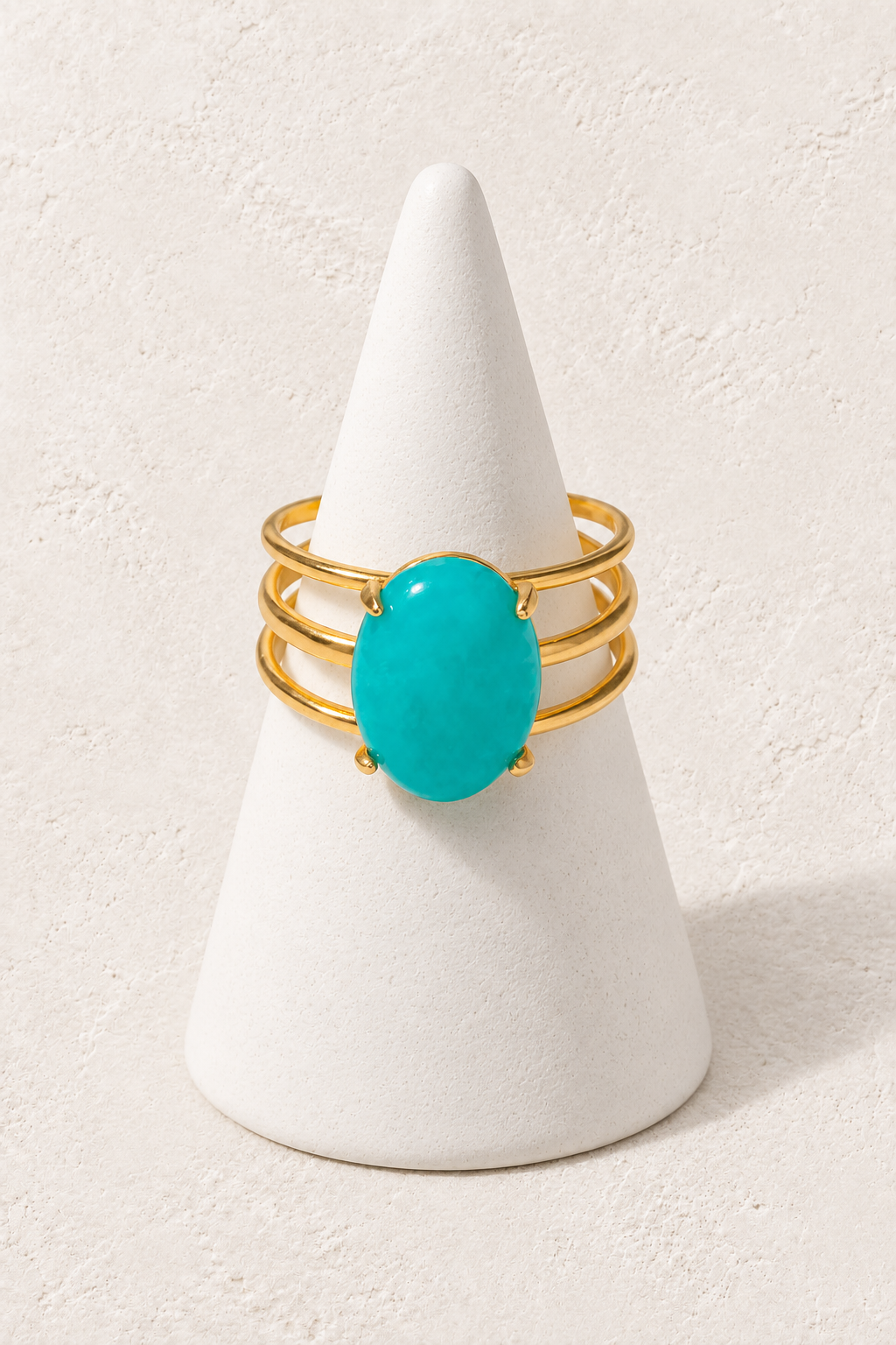 Marisol Turquoise Triple-Band Ring on a white display cone against a warm textured background