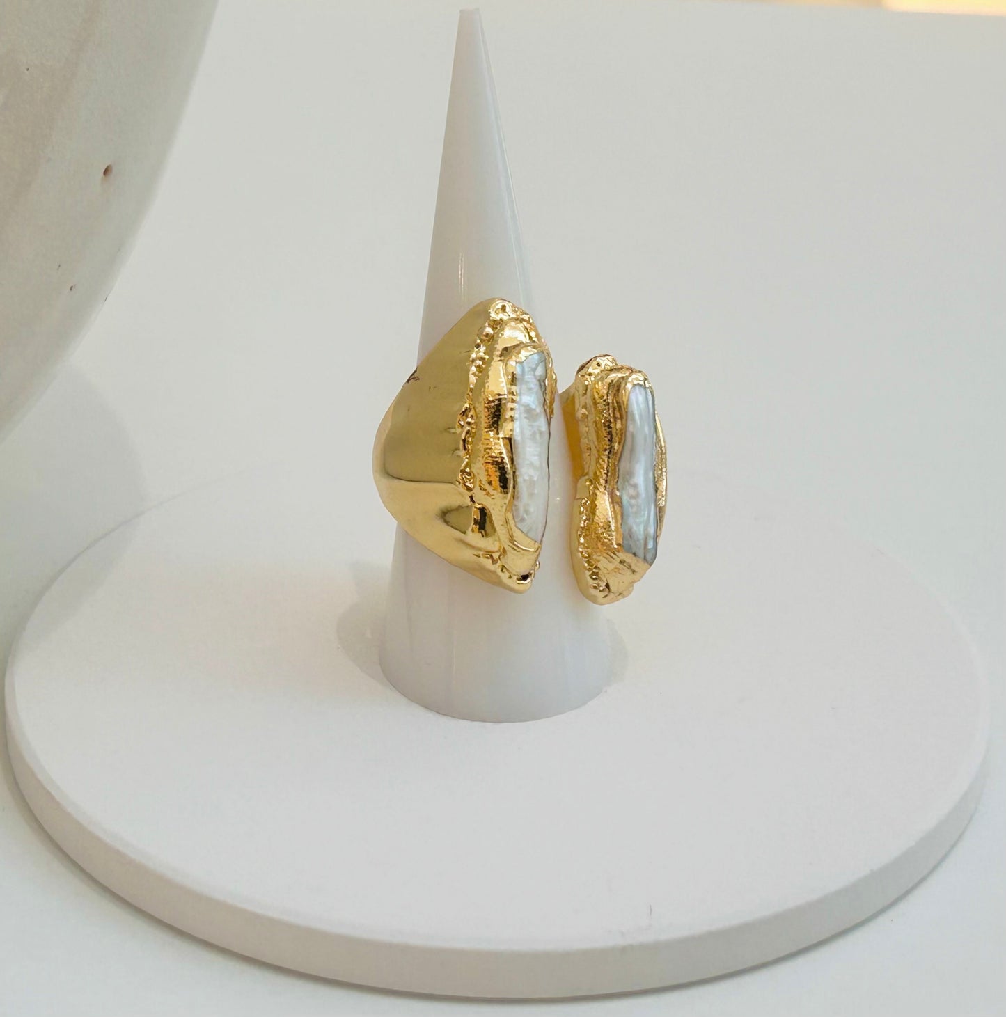
                  
                    Nerelle Biwa Pearl Statement Ring displayed on a white jewellery stand, featuring two elongated freshwater pearls in a sculptural gold-plated setting.
                  
                