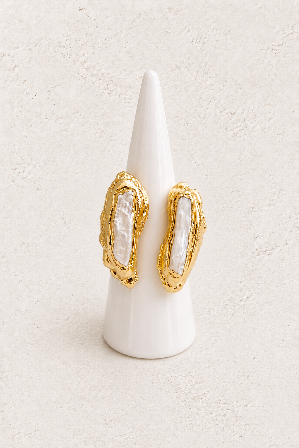 
                  
                    Nerelle Biwa Freshwater Pearl Ring on white cone against warm textured background
                  
                