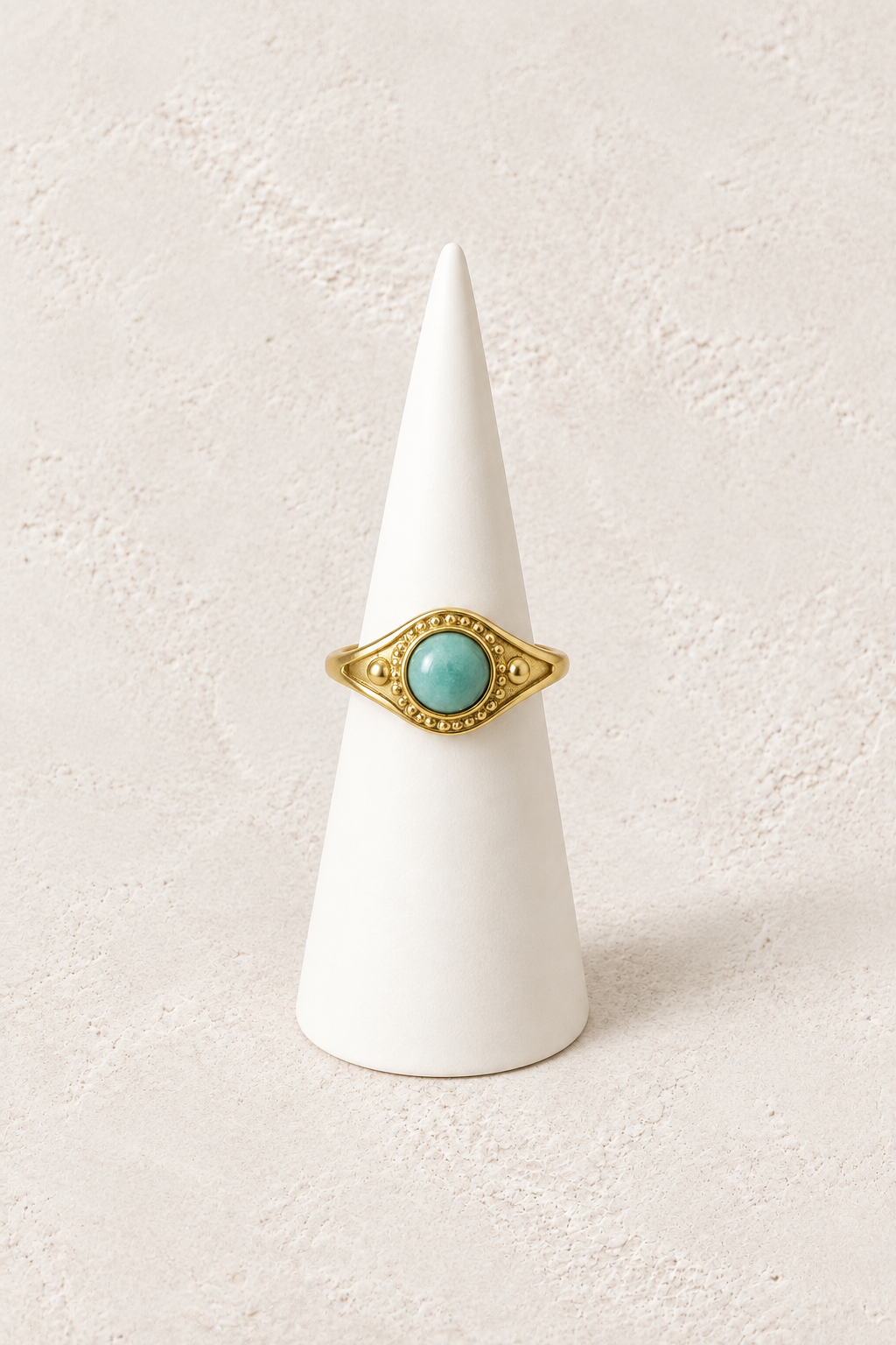 Nerissa Amazonite Eye Ring on a white display cone against a warm textured background