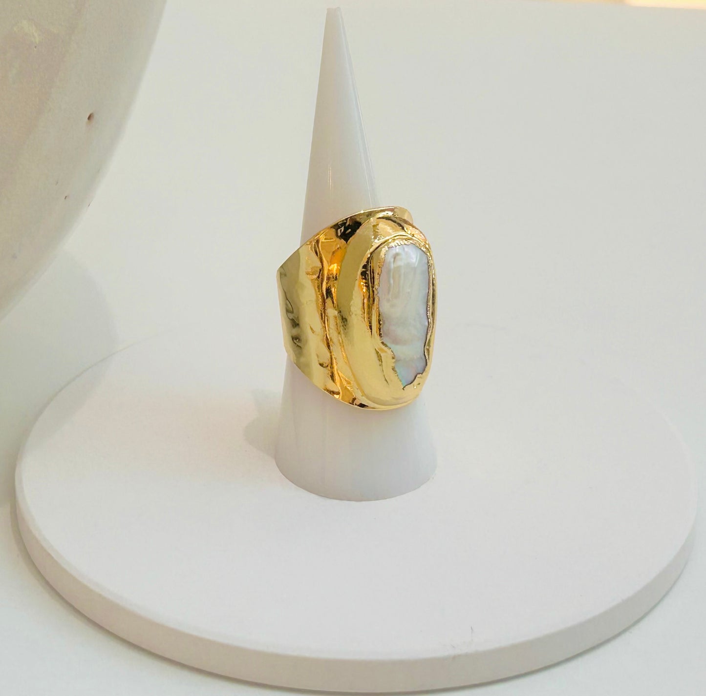
                  
                    Ondelle Biwa Pearl Statement Ring displayed on a white jewellery stand, featuring an elongated freshwater pearl in a wide sculptural gold-plated band.
                  
                